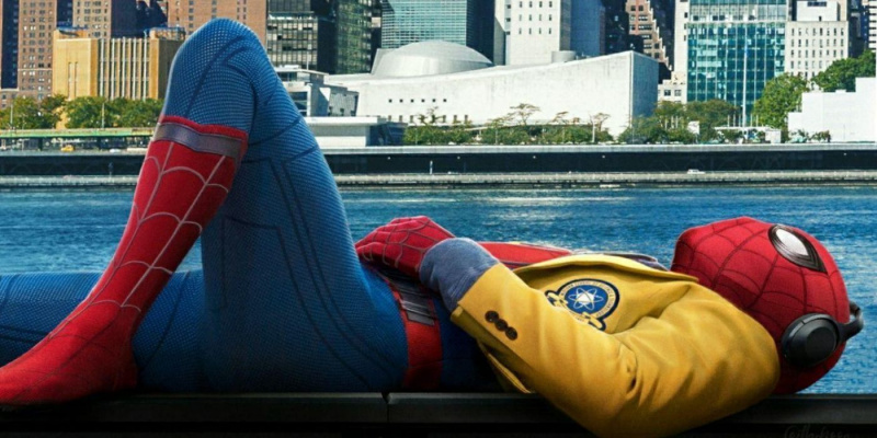   Spider-Man berbaring di dekat air mengenakan jaket SMA-nya dan mendengarkan musik